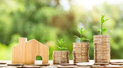 3 piles de pièces aligner à coté d'une petite maison en bois